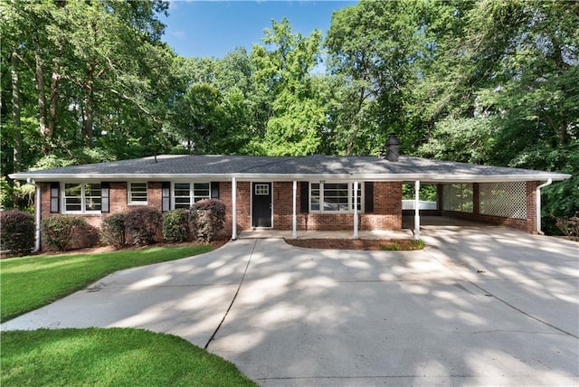 ranch-style home with driveway, brick siding, a chimney, a carport, and a front yard