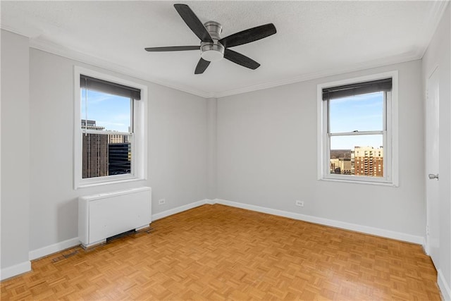 spare room with radiator heating unit, a ceiling fan, baseboards, and ornamental molding