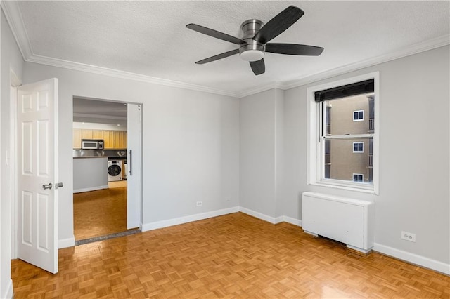 unfurnished bedroom featuring baseboards, washer / dryer, radiator heating unit, a textured ceiling, and crown molding