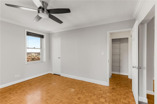 unfurnished bedroom featuring a textured ceiling, a ceiling fan, baseboards, and ornamental molding