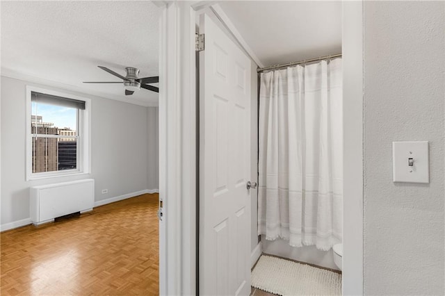 full bathroom featuring baseboards, radiator, a textured ceiling, and ceiling fan