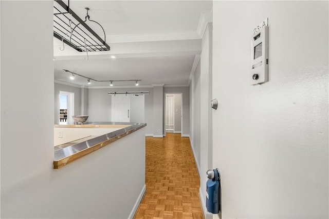 hallway with rail lighting, baseboards, and ornamental molding