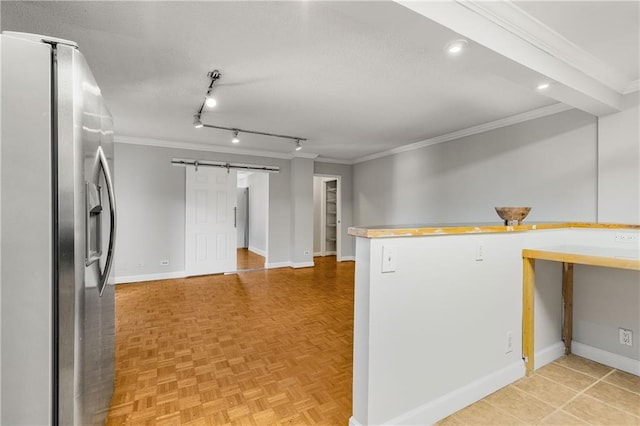 kitchen featuring a barn door, crown molding, stainless steel fridge, and baseboards