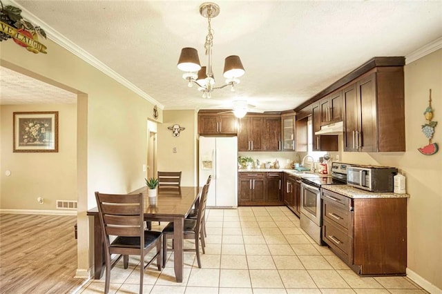 kitchen featuring light tile patterned floors, stainless steel appliances, hanging light fixtures, and ornamental molding