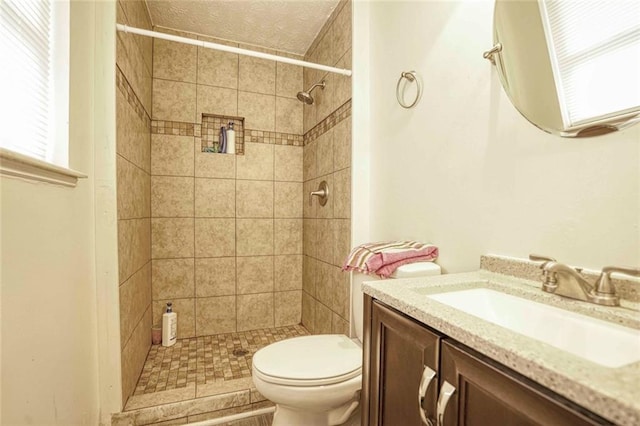 bathroom with vanity, toilet, and tiled shower