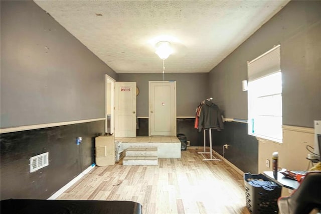 misc room featuring light wood-type flooring and a textured ceiling