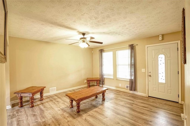 interior space with light wood-type flooring, a textured ceiling, and ceiling fan