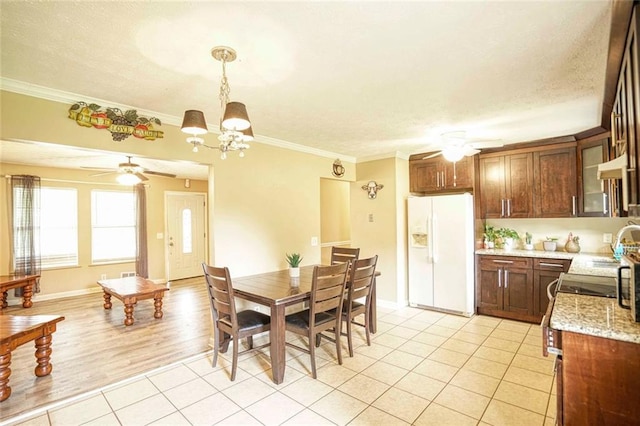 tiled dining room with ceiling fan with notable chandelier, ornamental molding, and a textured ceiling