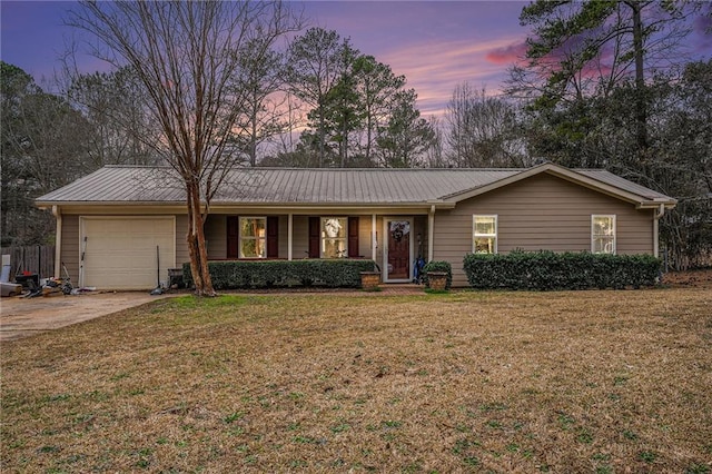 single story home with concrete driveway, a lawn, an attached garage, and metal roof