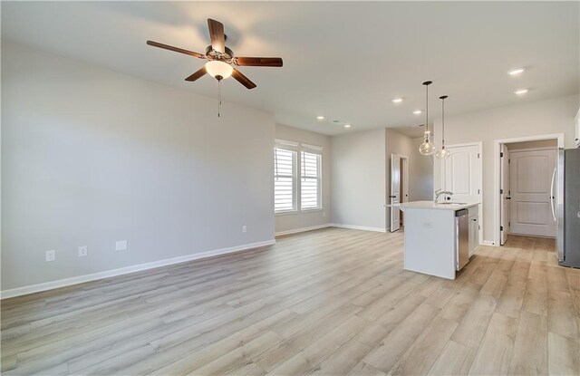 unfurnished living room with ceiling fan, sink, and light hardwood / wood-style flooring