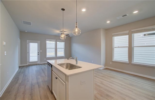 kitchen featuring white cabinetry, sink, ceiling fan, hanging light fixtures, and a kitchen island with sink