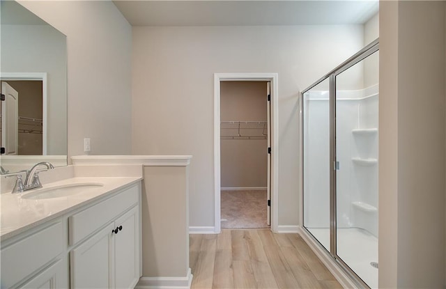 bathroom with hardwood / wood-style floors, vanity, and a shower with shower door