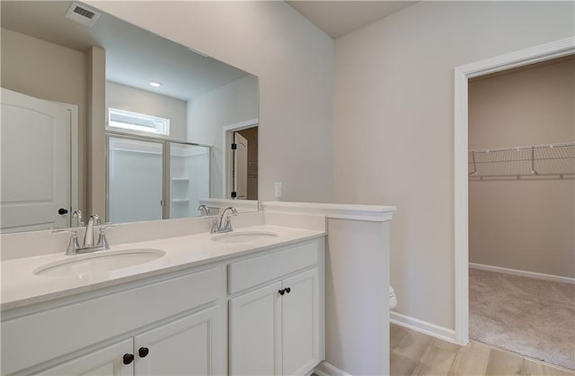 bathroom with wood-type flooring, vanity, a shower with shower door, and toilet