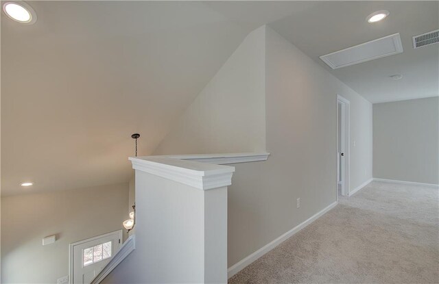 hallway with light colored carpet and vaulted ceiling