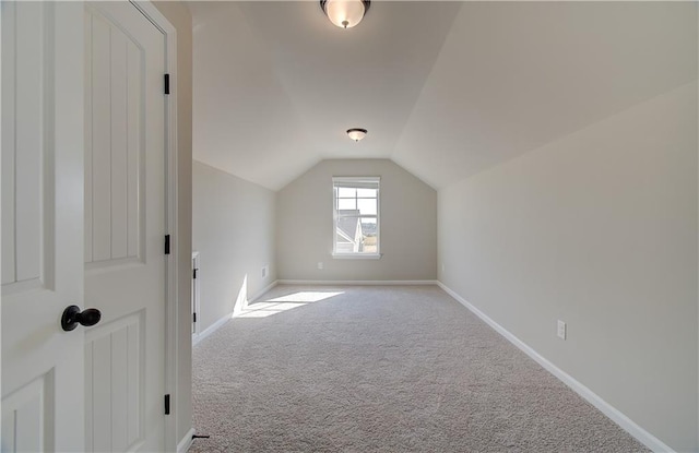 bonus room with light colored carpet and vaulted ceiling