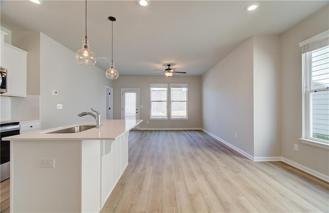 kitchen featuring a wealth of natural light, sink, pendant lighting, white cabinetry, and an island with sink