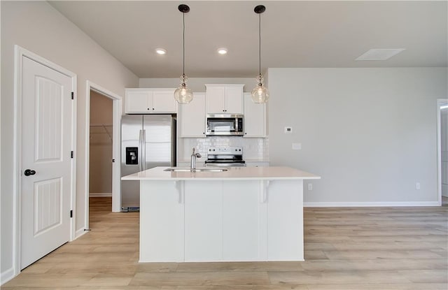 kitchen with white cabinets, a kitchen island with sink, sink, and appliances with stainless steel finishes