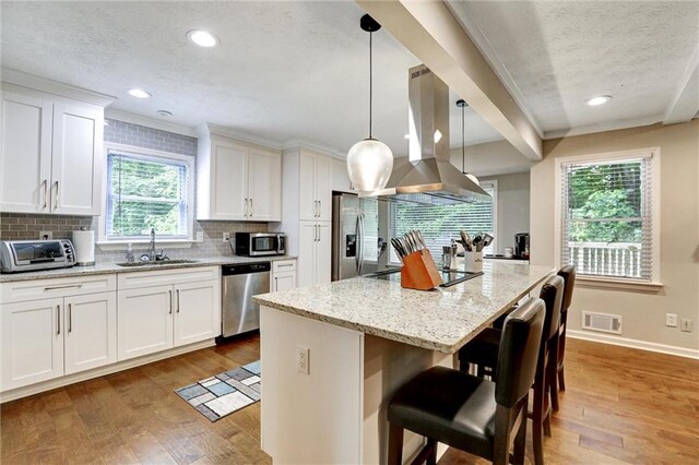 537 Raven Springs Trl, Stone Mountain, GA 30087 - kitchen with island exhaust hood, appliances with stainless steel finishes, a textured ceiling, wood finished floors, and a kitchen island