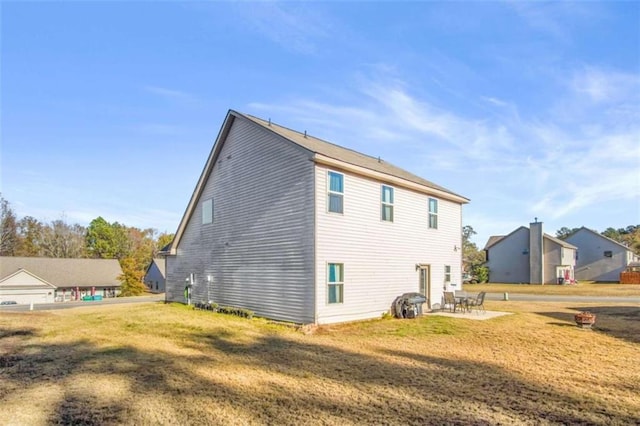 back of house with a lawn and a patio