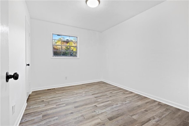 spare room with baseboards and wood finished floors