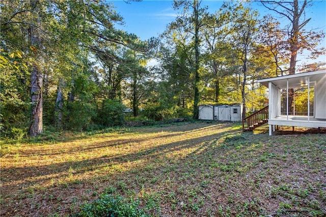 view of yard with a sunroom, a storage unit, and an outbuilding