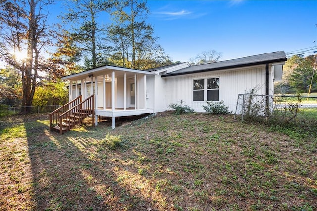 rear view of house featuring fence and a yard