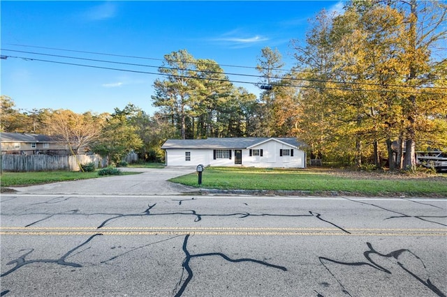 view of front of property featuring fence, driveway, and a front lawn