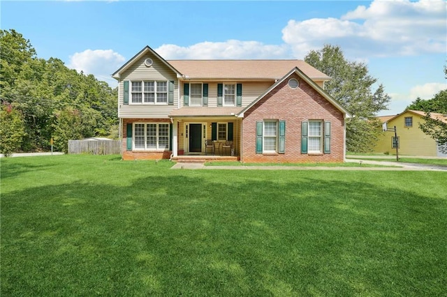 rear view of house with covered porch, a lawn, and brick siding