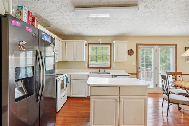 kitchen featuring a textured ceiling, white appliances, sink, white cabinetry, and light wood-type flooring