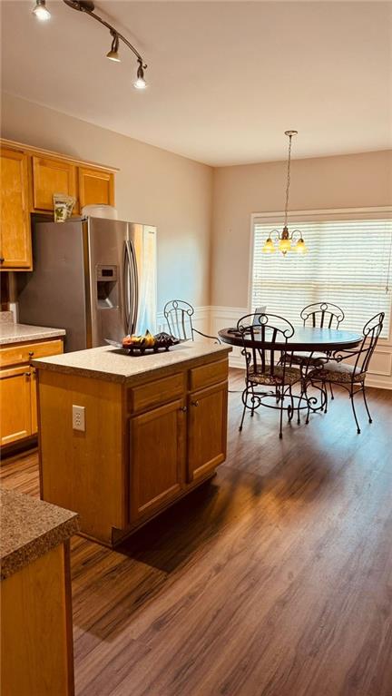 kitchen with pendant lighting, dark hardwood / wood-style floors, a center island, and stainless steel fridge with ice dispenser