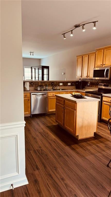 kitchen with stainless steel appliances, kitchen peninsula, a center island, sink, and dark hardwood / wood-style floors