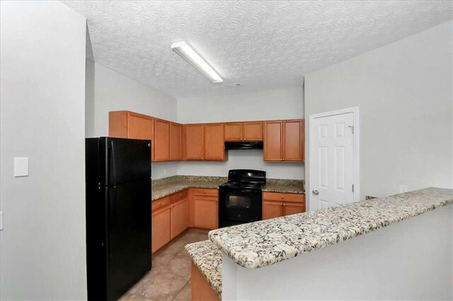 kitchen featuring light stone counters, a textured ceiling, kitchen peninsula, and black appliances