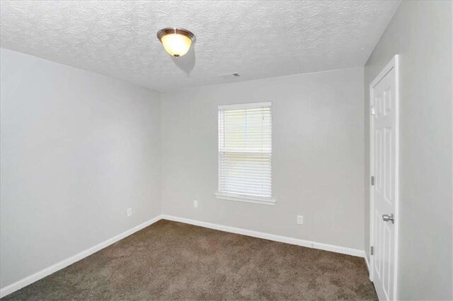 empty room featuring dark carpet and a textured ceiling