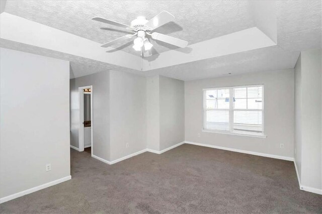 carpeted spare room with a textured ceiling, a raised ceiling, and ceiling fan