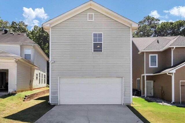 back of house with a garage and a yard