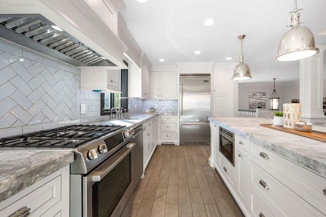 kitchen featuring white cabinets, custom exhaust hood, stainless steel appliances, and light stone counters