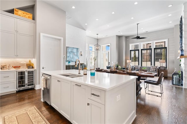 kitchen with a sink, dark wood-type flooring, stainless steel dishwasher, and beverage cooler