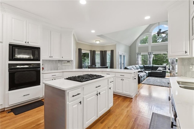 1213 Grande Vw, Loganville, GA 30052 - kitchen with black appliances, a kitchen island, light countertops, open floor plan, and recessed lighting
