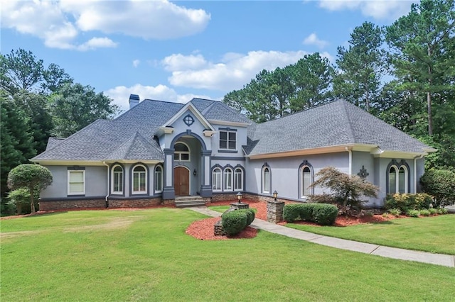1213 Grande Vw, Loganville, GA 30052 - view of front of property featuring stucco siding, a front yard, a chimney, and a shingled roof