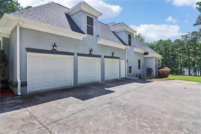 1213 Grande Vw, Loganville, GA 30052 - view of side of home with a shingled roof, stucco siding, driveway, and an attached garage