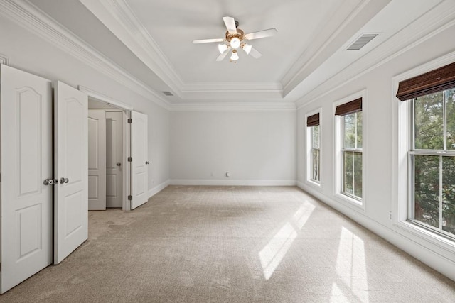 unfurnished bedroom with crown molding, ceiling fan, a raised ceiling, and light carpet