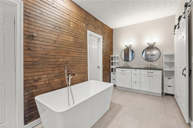 bathroom with vanity, a textured ceiling, a bathtub, and wooden walls