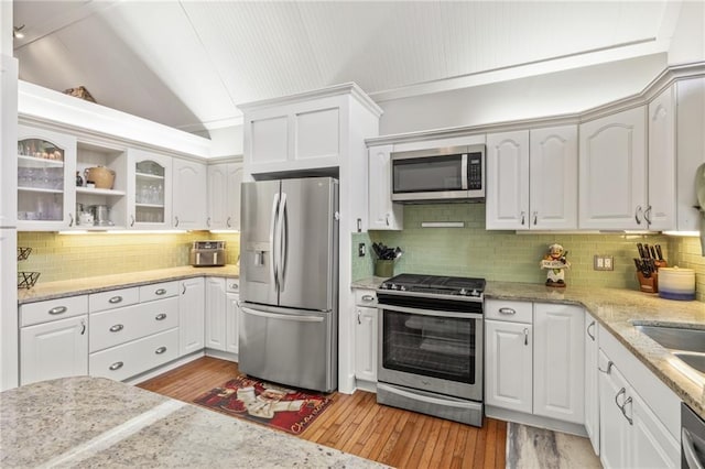 kitchen with white cabinets, lofted ceiling, stainless steel appliances, and light hardwood / wood-style flooring