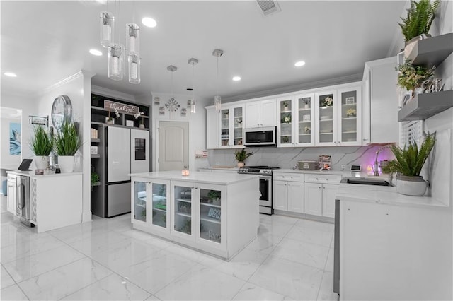 kitchen with white cabinets, stainless steel appliances, hanging light fixtures, and a kitchen island