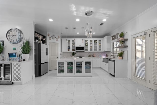 kitchen featuring white cabinets, hanging light fixtures, a kitchen island, appliances with stainless steel finishes, and wine cooler