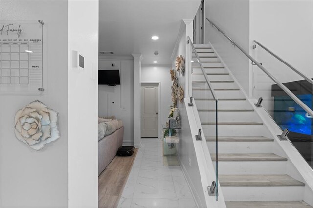 stairs featuring hardwood / wood-style floors and crown molding