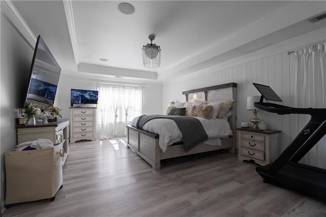 bedroom with a tray ceiling, hardwood / wood-style floors, and ornamental molding