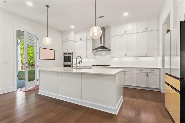 kitchen featuring wall chimney exhaust hood, double oven, visible vents, dark wood-style flooring, and a sink