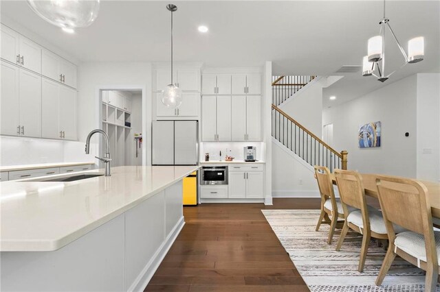 kitchen with white cabinets, dark wood-type flooring, refrigerator, and a sink