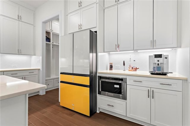kitchen with dark wood-style floors, light countertops, freestanding refrigerator, and backsplash